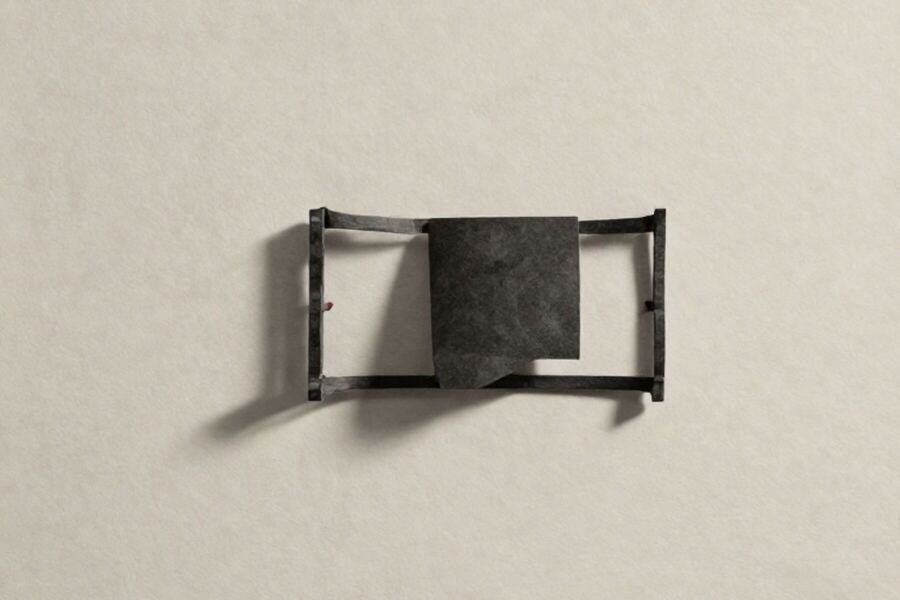 A solid paper form held inside a large open bracket cut from card