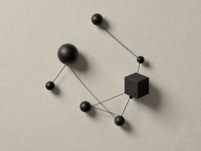Small spheres and one cube arranged in a constellation and joined by taut black thread