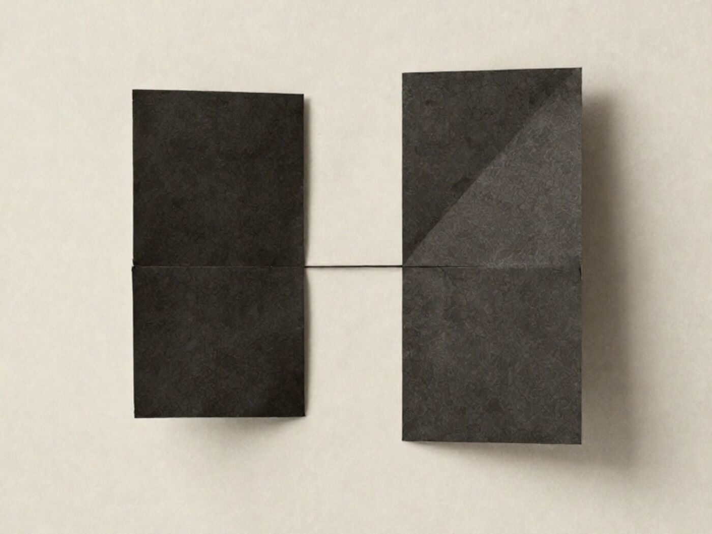 Two folded paper forms of different geometry either side of a single hairline seam