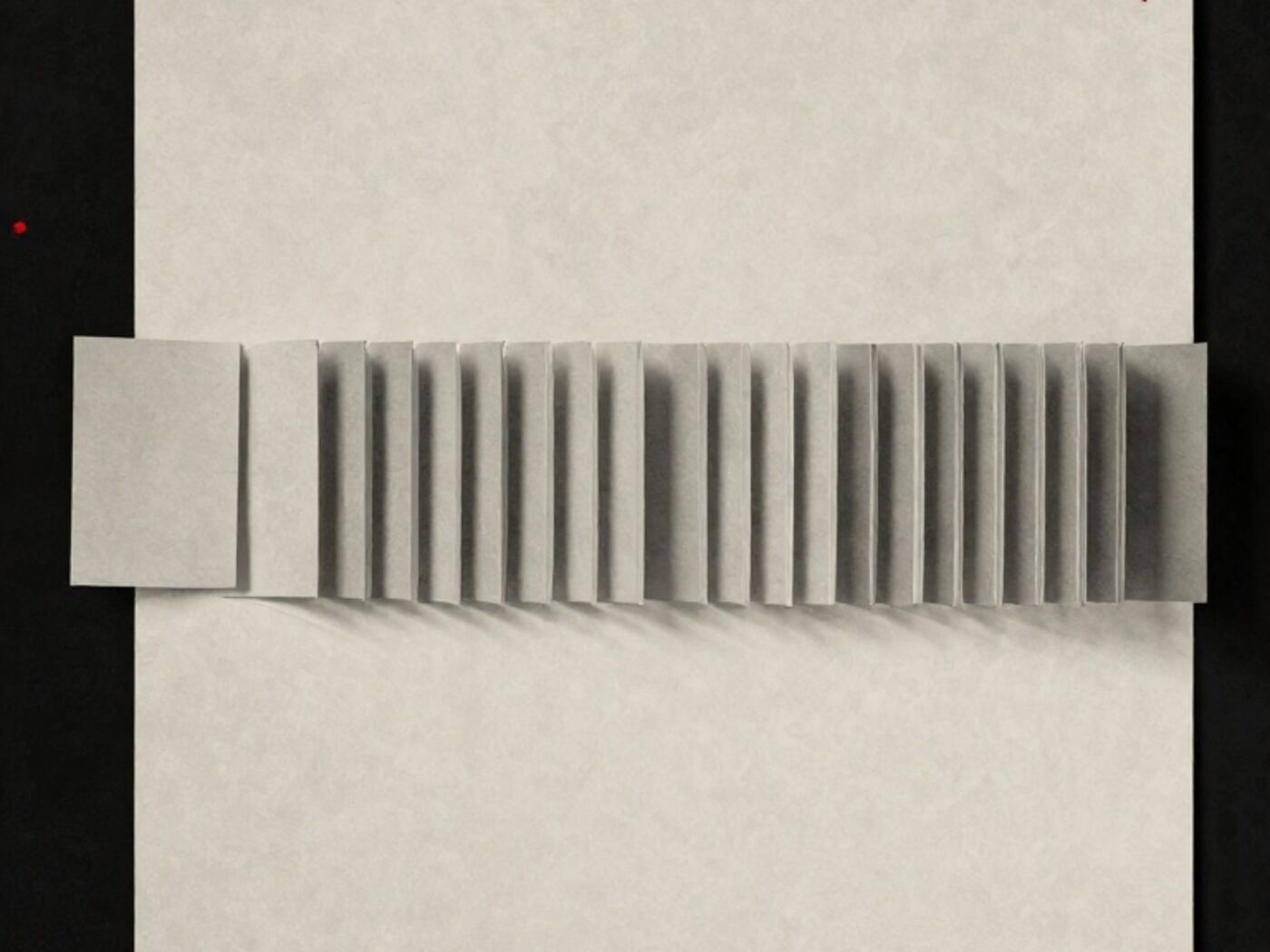 A row of identical paper cards lying flat, with one lifted and standing on its edge